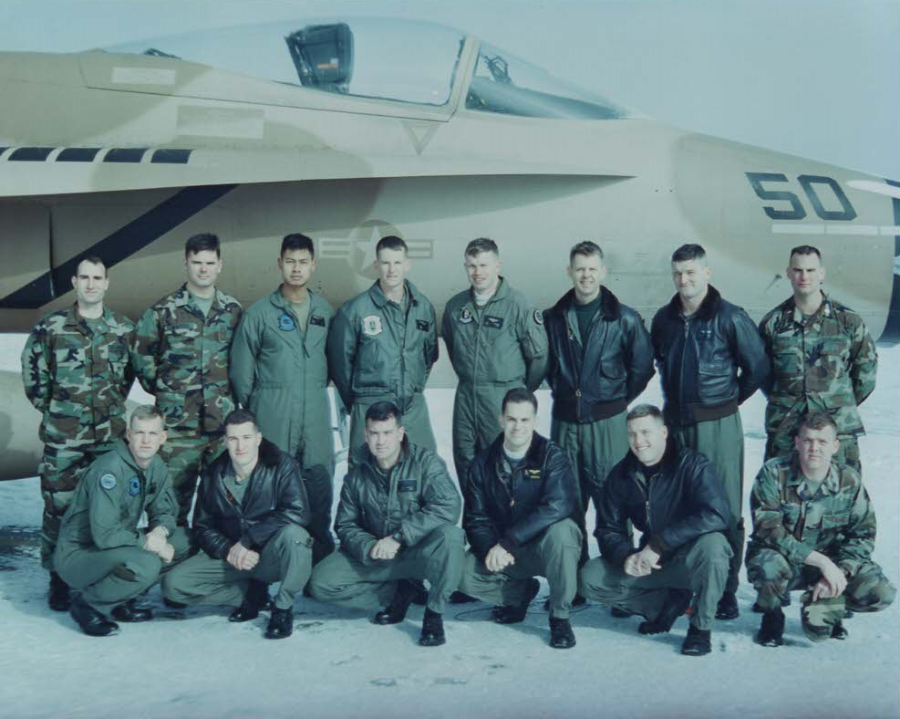 A group of men posing in front of a plane